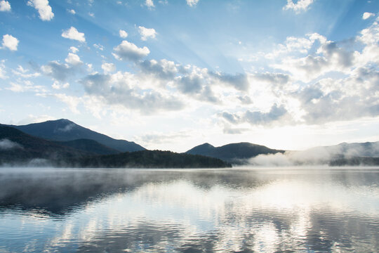United States, New York, Lake Placid, Mountains and clouds reflected in calm Lake Placid at sunrise