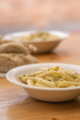 Plato de pasta en plato blanco con especias y pan de fondo desenfocado