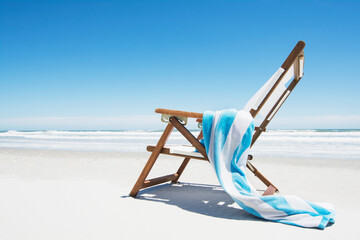 Empty beach chair with striped towel on beach