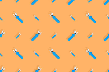 Background from a metal adjustable wrench with a rubber handle. Tools seamless pattern.