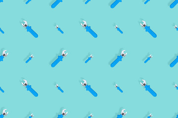 Background from a metal adjustable wrench with a rubber handle. Tools seamless pattern.