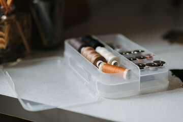 Closeup of the colorful sewing threads in the plastic container