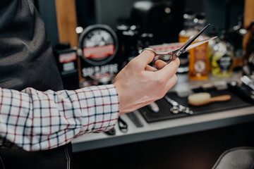 Barber holding scissors. Barbershop equipment. Close-up hairdresser tools. Selective focus