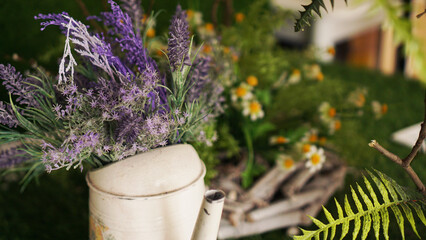 Lavender in an old teapot. Green grass and chamomile on a blurred background