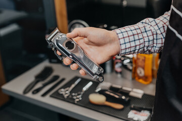 Fototapeta na wymiar Barber holding electric razor. Barbershop equipment. Close-up hairdresser tools. Selective focus