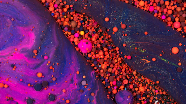 Abstract background of bobbly and mixed orange, purple and pink oily paints