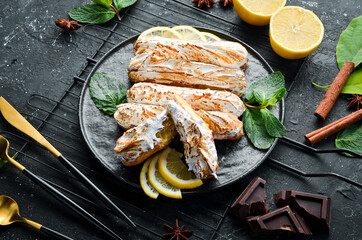 Eclair with lemon cream. Lemon dessert on a black stone plate. Top view. Rustic style.