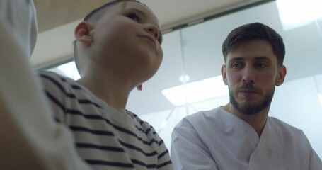 Close-up a male medical worker who is speaking with a little boy before the dentist visit.
