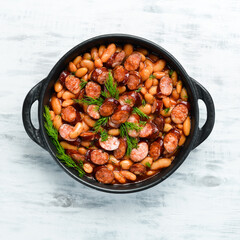 Beans with sausages in tomato sauce on a black plate.  Top view. Free space for your text.