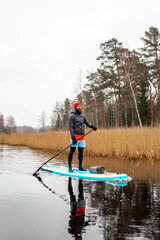 Young men paddle with SUP or stand up paddle board in small river. concept of harmony with the nature. Stand up paddle boarding - awesome active outdoor recreation.