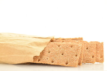 Several multigrain thin crisps in a paper bag, close-up, isolated on white.