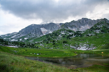 panoramic view of the mountain lake with tourist tents a cloudy summer day. Adygea, Russia.