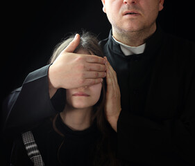 priest covers the mouth of a young girl with his hand - 426127452