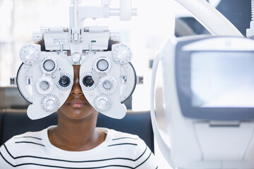 Happy young woman african american eye exam with diagnostic ophthalmology in optical clinic. professional ophthalmic checking vision. phoropter machine, Eye health check and ophthalmology concept.