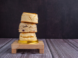 Side view of scones traditional English delicious fresh bake homemade on mini wooden table with dark vintage wall background. Dessert, beverage, and relaxation concept