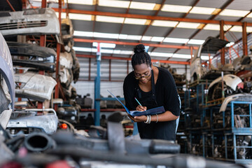 African american worker woman wear spectacles make a note of the product list on clipboard in factory auto parts. female employee business warehouse motor vehicle. - Powered by Adobe