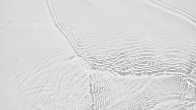 Up close, top view, Slow motion various waves of the water surface hitting the sun's rays, making them sparkle according to different patterns on a gray background video 4K.
