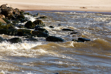 Rocky sea shore with large rocks and waves in windy weather