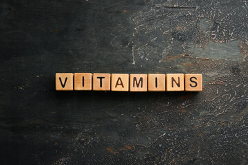 The inscription "VITAMIN" is laid out of wooden cubes. Top view.