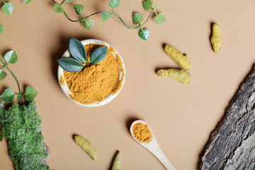  health care lifestyle concept. Curcuma Longa or turmeric powder in bowl with green leaf,wooden spoon and turmeric root on beige background.