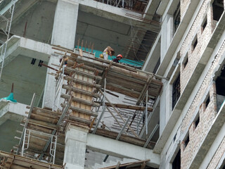 MALACCA, MALAYSIA -MARCH 14, 2020: Construction workers working at height at the construction site. They are supplied with harnesses and other safety equipment to prevent them from having an accident.