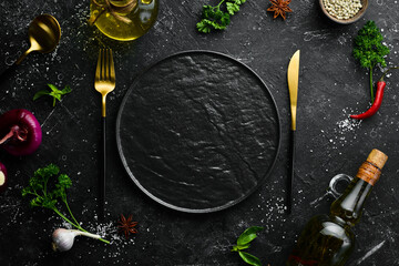 Cutlery and black plate on a black stone background. Top view. Free space for text.
