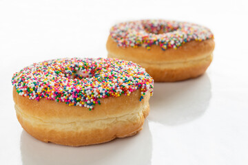 Donuts with colorful sprinkles on white background with copy space.