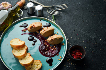 Goose liver pate with soy sauce and toast on a black stone background. Top view. Rustic style.