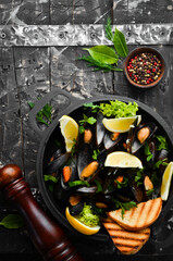 Boiled mussels with garlic, parsley and lemon in a frying pan. Top view. Free space for your text.