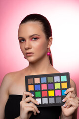 Pretty woman wearing round pink earrings holding a colorchecker