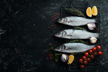 Sea bass fish with spices and herbs. Preparation. On a dark kitchen background. Top view.