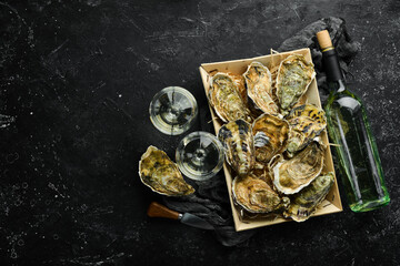 Closed fresh oysters and white wine in glasses on a stone background. Free space for your text....