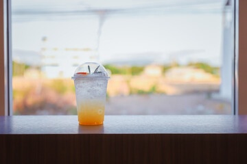Orange juice mix soda placed on a wooden table by the window.