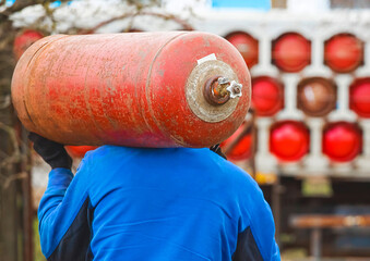 A male industrial worker walks with a gas cylinder to a gas car. Transportation and installation of...