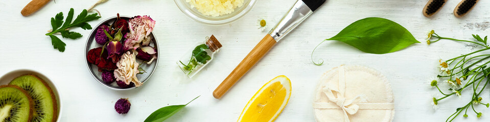 Concept of natural organic ingredients for homemade face and body care products. Essential oils, fruits, vegetables, flowers for skin purifying and moisturizing. White background, flat lay banner