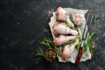 Raw chicken drumsticks with rosemary, spices and vegetables. Top view. Free space for your text.