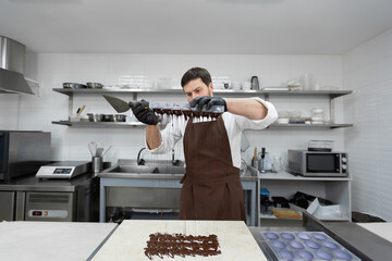 Chef or chocolatier makes sweet chocolates in a professional kitchen.