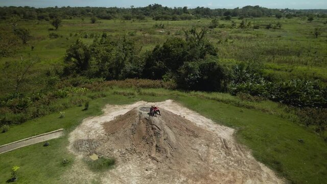 A couple sits atop a cone shaped mud volcano aerial 360 pan view