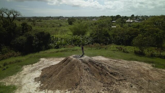 Helix aerial view of a woman standing in a mud volcano in the forest