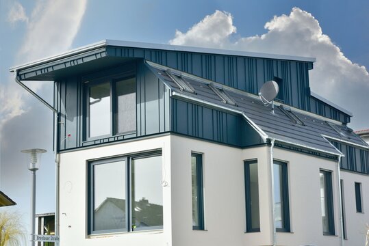 Teilweise Stehfalz-Metall-Verkleidung des Dachgeschosses an einem aussergewöhnlichen modernen Einfamilienhaus