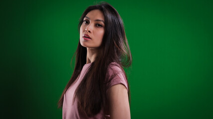 Young pretty woman in the studio posing against a green background - studio photography