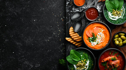 Set of colored soups. Spinach soup, tomato cream soup and carrot puree soup. Healthy food. On a black stone background.