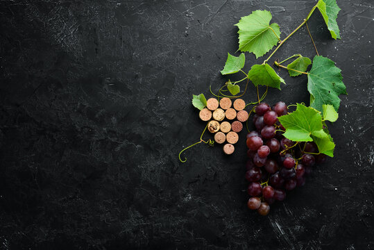 Fresh red grapes with leaves on a black stone table. Top view. Free space for your text.