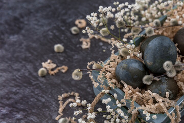 Easter composition with dark colored eggs in a wooden box. Willow branch. The minimal concept of Easter. An Easter card with a place for the text.