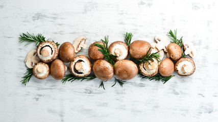 Fresh champignon mushrooms on a white wooden background. Organic food. Rustic style. Top view.
