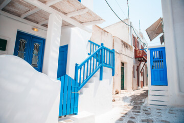 The narrow streets of the island with blue balconies, stairs and flowers in Greece.
