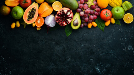 Vegetables and fruits, healthy food. Fruits and vegetables on black stone background. Tropical...