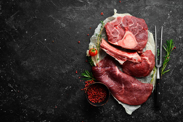 Meat. Fresh raw veal steaks and meat. Top view. Flat lay top view on black stone cutting table.