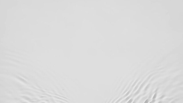 Up close, top view, Slow motion various waves of the water surface hitting the sun's rays, making them sparkle according to different patterns on a gray background video 4K.