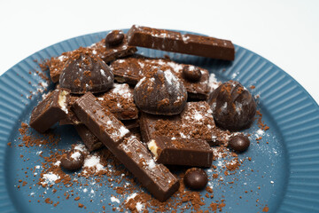 Composition of bars and pieces of different milk and dark chocolate, cocoa grater on a white background, top view
